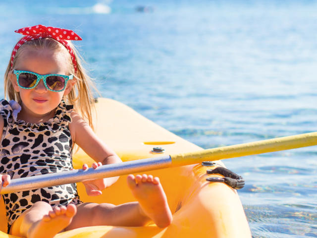 Little cute girl kayaking in the clear blue sea