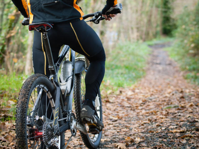 Cyclist standing in front of a path of the forest with a copy space on your right