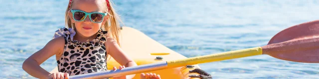 Little cute girl kayaking in the clear blue sea